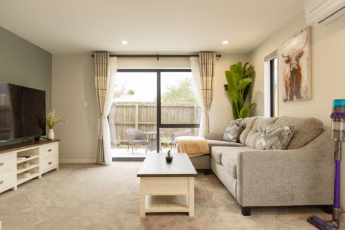 a living room with a couch and a tv at Brand New 3BR Home with Parking in Christchurch