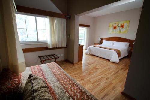 a bedroom with two beds and two windows at La Campiña Club Hotel & Spa in Santa Rosa