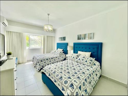 two beds in a bedroom with blue and white sheets at Beautiful Two bedrooms apartment in Punta Cana