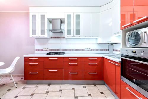 Una cocina con gabinetes rojos y un microondas. en Duplex on Main Square, en Leópolis