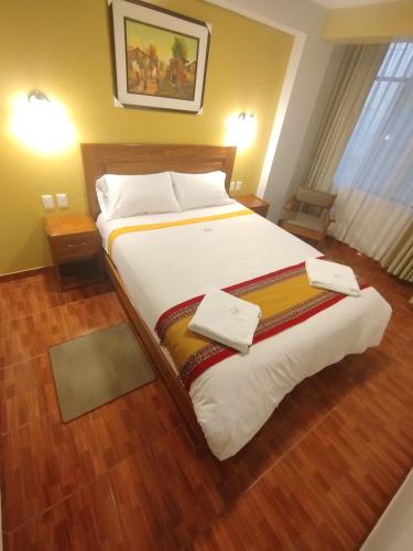 a bedroom with a large bed with two towels on it at Picos House MachuPicchu in Machu Picchu