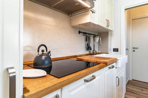 a kitchen with white cabinets and a tea kettle on the counter at Fiore del Brenta 2 a 50 m dalla fermata dello skibus gratuito in Andalo