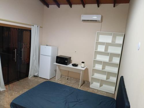 a room with a bed and a desk and a refrigerator at Suite con baño privado in Puerto Presidente Franco