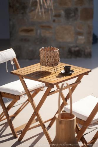 a wooden table with a chair and a cup on it at ELLI TROPiCAL LUXURY SUITES SUNSET-INFINITY POOL- SEA SIDE-NEAR CENTER PARKING in Mikonos
