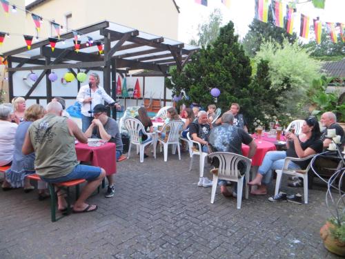 a group of people sitting at tables in a garden at Landgasthaus Zur Kupferkanne in Kobern-Gondorf