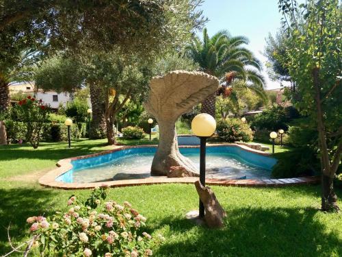 a garden with a swimming pool with a palm tree at Sea&Sage 4 Spiagge Raggiungibili a piedi, Per famiglie con tutti i servizi in Porto San Paolo