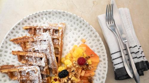 een wit bord met wafels, fruit en een vork bij Casa Bonita Hotel & Luxury Residence in Oaxaca City