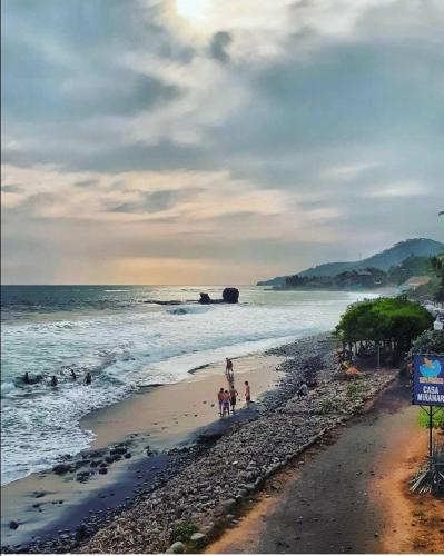 a group of people on a beach near the ocean at Hotel Casa Miramar in Tamanique