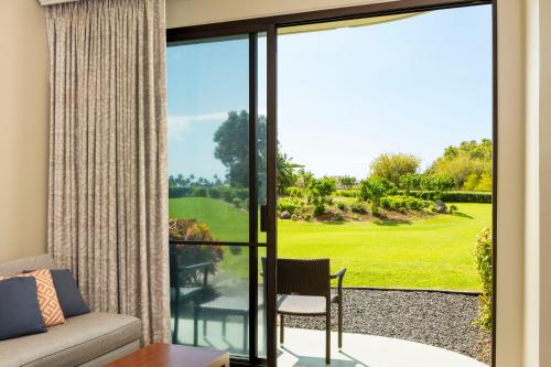 a living room with sliding glass doors looking out onto a golf course at Hilton Waikoloa Village in Waikoloa