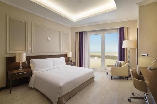 a bedroom with a large white bed and a chair at Hilton Al Khobar King Fahd Causeway in Al Khobar