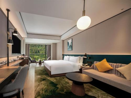 a hotel room with a bed and a couch at Hilton Garden Inn Zhangjiajie Wulingyuan in Zhangjiajie