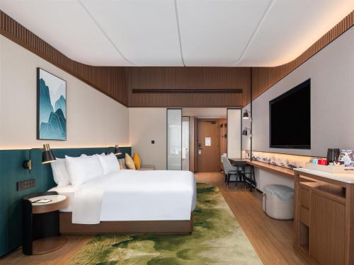 a hotel room with a large bed and a bathroom at Hilton Garden Inn Zhangjiajie Wulingyuan in Zhangjiajie