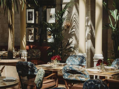 a dining room with tables and chairs and plants at NoMad London in London