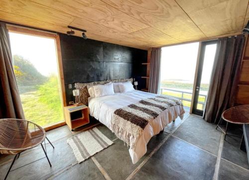 una camera da letto con un letto grande e una grande finestra di B Lodge a Queilén