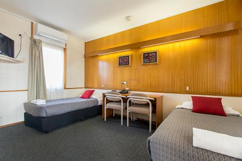 um quarto com 2 camas, uma secretária e uma mesa em Citrus Valley Motel em Renmark