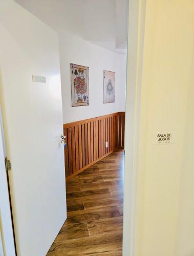 a room with a hallway with wooden floors and paintings on the wall at Studio Home 64 Luxo in Mogi das Cruzes