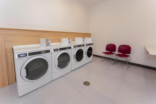 a laundry room with three washing machines and two red chairs at Hampton Inn & Suites Irving Hwy 183 in Irving