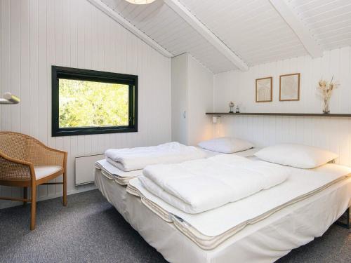 6 person holiday home in Nørre Nebel في Nørre Nebel: غرفة نوم بيضاء بسريرين وكرسي