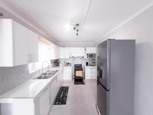 a kitchen with white cabinets and a stainless steel refrigerator at Magodi Place - Serviced & Airconditioned Apartment in Livingstone