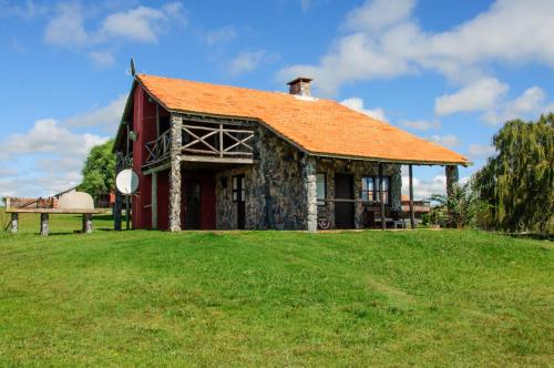 a red barn with an orange roof on a green field at San Francisco De Las Sierras in Minas