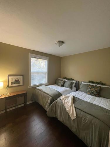 a bedroom with two beds and a table and a window at Mins to Downtown & Raceway Rookwood Retreat 2 in Indianapolis