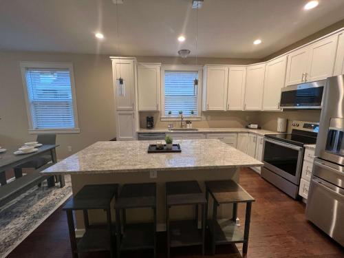 a kitchen with white cabinets and a kitchen island with bar stools at Mins to Downtown & Raceway Rookwood Retreat 2 in Indianapolis