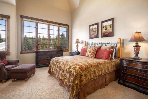 Un dormitorio con una cama y una silla y ventanas. en Base Camp 490 Private Hot Tub, en Winter Park