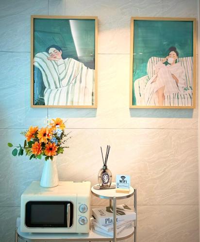 a table with a microwave and a vase with flowers at HausKomma 서울 홍대,이태원,명동 짐보관 무료 주차 엘레베이터 새아파트 in Seoul