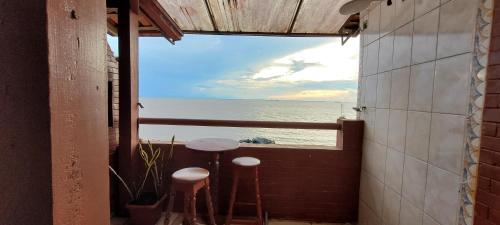 Una vista del océano desde un balcón con taburetes. en Apartamento ideal para famílias em mosqueiro, com piscinas e em frente a praia, en Mosqueiro