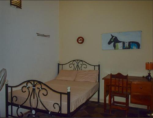 a bedroom with a bed and a table and a picture of a horse at Casa Oasis Colonial in El Venado