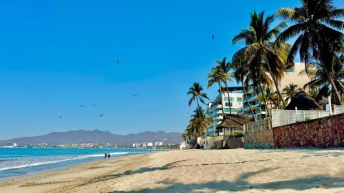 a sandy beach with palm trees and the ocean at Beach Loft LIFE Bucerías - Zona Dorada in Bucerías
