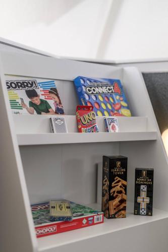 a book shelf with some games and books at Dome Manor 2 Game Rooms, Hot Tub & Pool! in Bedford