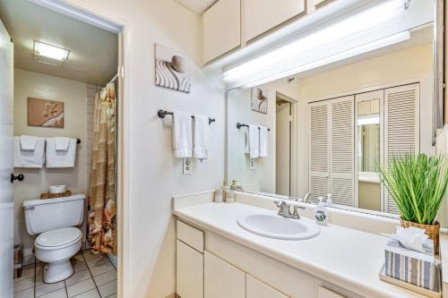 ein Badezimmer mit Waschbecken, Toilette und Spiegel in der Unterkunft Walkers Paradise Maui at Valley Isle Resort in Lahaina
