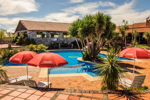 a swimming pool with two red umbrellas in front of a house at San Francisco De Las Sierras in Minas