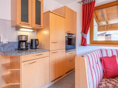 a small kitchen with wooden cabinets and a couch at Obinghof in Söll