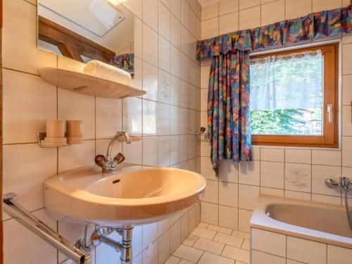 La salle de bains est pourvue d'un lavabo, d'une baignoire et d'une fenêtre. dans l'établissement Appartement Brixnerwirt III, à Brixen im Thale