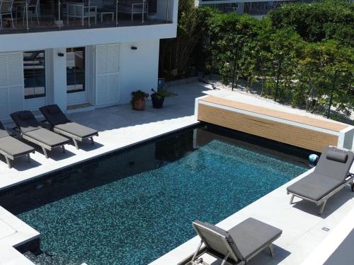 une piscine avec des chaises et un banc et une maison dans l'établissement Villa les Oiseaux, aux Issambres