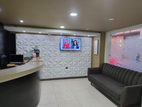 a waiting room with a couch and a tv on a wall at Hotel Rialto Suite in Pasto