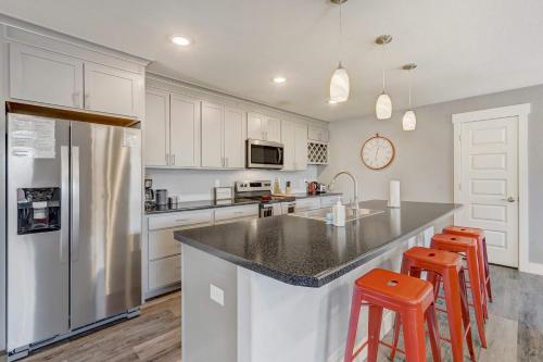 a kitchen with white cabinets and a counter with stools at Vermijo Flat Walk to Downtown Shops & Dining in Colorado Springs