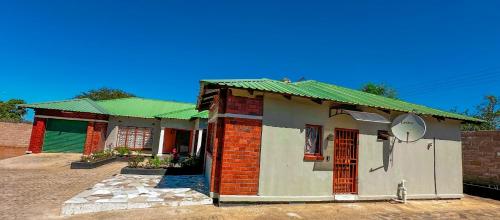 a small brick house with a green roof at Magodi Place - Serviced & Airconditioned Apartment in Livingstone