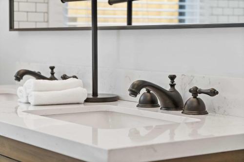 a bathroom sink with two faucets and a mirror at 5 Minutes to Campbell - Clarksville Craftsman in Clarksville