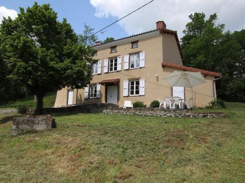 a large house with two chairs and an umbrella at Maison de campagne avec grande terrasse, près de Lavaudieu et accessible PMR - FR-1-582-217 in Mazerat-Aurouze