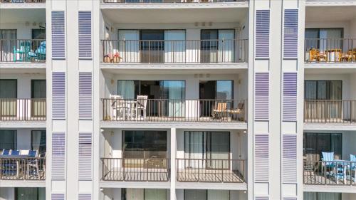 a tall white apartment building with balconies and tables at Ocean View 3BR Condo with Pool in North Ocean City in Ocean City