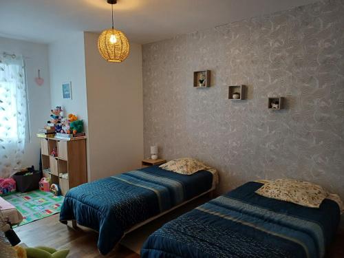 two beds in a childs bedroom with blue sheets at Appartement au coeur de Cours La Ville in Cours la Ville