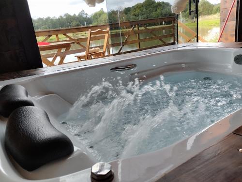 a bath tub with water in it with a window at Rancho dos lagos in Campo Alegre