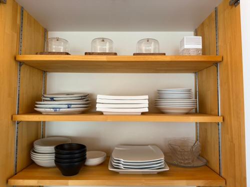 a cabinet filled with plates and dishes on wooden shelves at Soukyu 蒼穹 #TB1 in Yonago