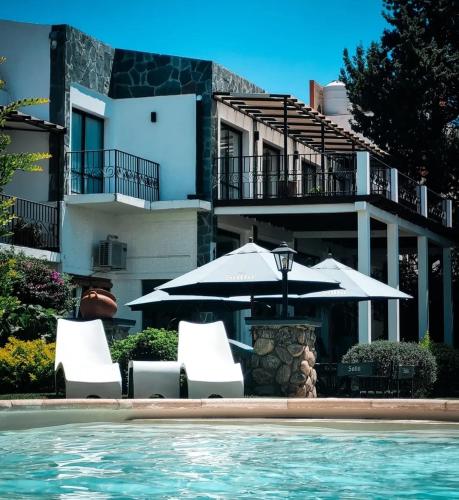 a swimming pool with two chairs and an umbrella at Hotel Los Sauces in Cafayate