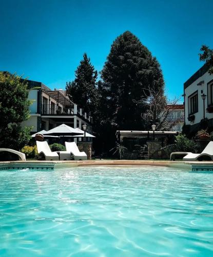 a swimming pool with chairs and an umbrella at Hotel Los Sauces in Cafayate