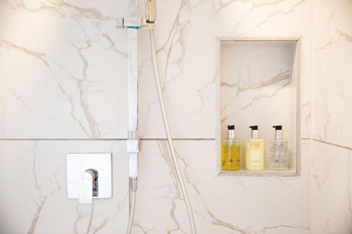 a bathroom with white marble walls and a shelf with bottles at Are Ara - House of Pineapple in Titikaweka