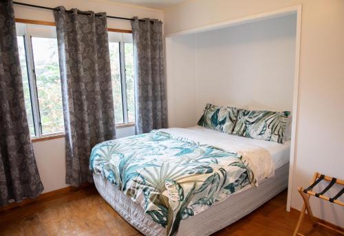 a bedroom with a bed and two windows at Are Ara - House of Pineapple in Titikaweka